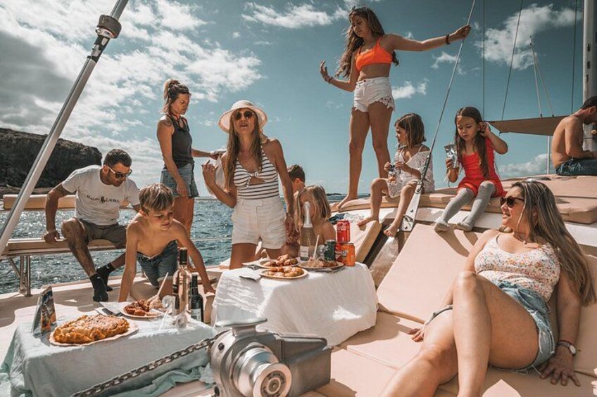 Un groupe de personnes se trouve sur un bateau, avec de la nourriture et des boissons sur le pont. 4