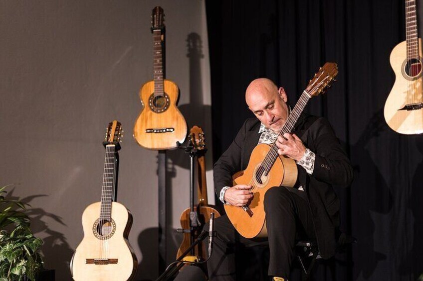 A man playing a guitar on stage with multiple guitars in the background. 3