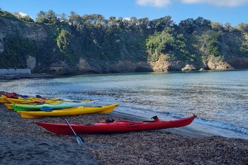 A beach with kayaks and a rocky cliff in the background. 2