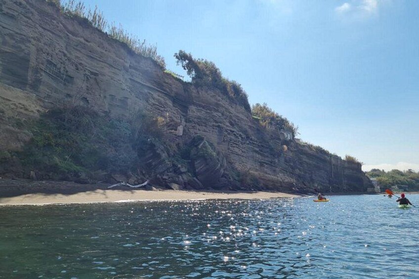 A rocky coastline with kayakers on the water. 4