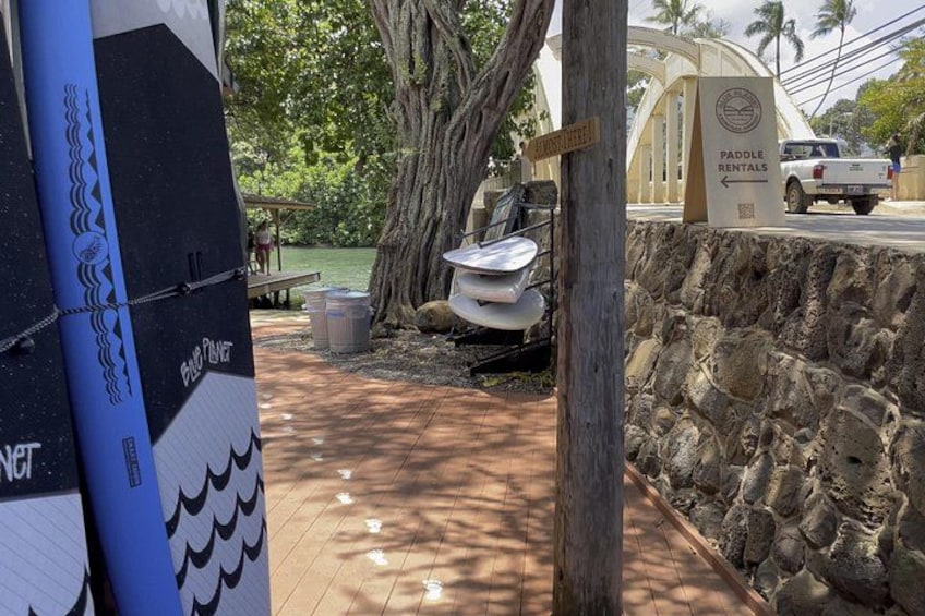 A paddleboard rental sign, a surfboard, a truck, and a stone wall. 4