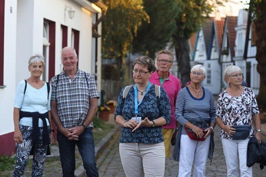 A group of people standing on a cobblestone street in a European town. 1