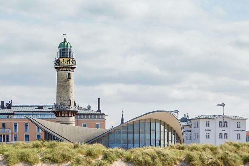 A modern building with a curved glass facade, a historic tower with a green dome, and a hotel in the background. 3
