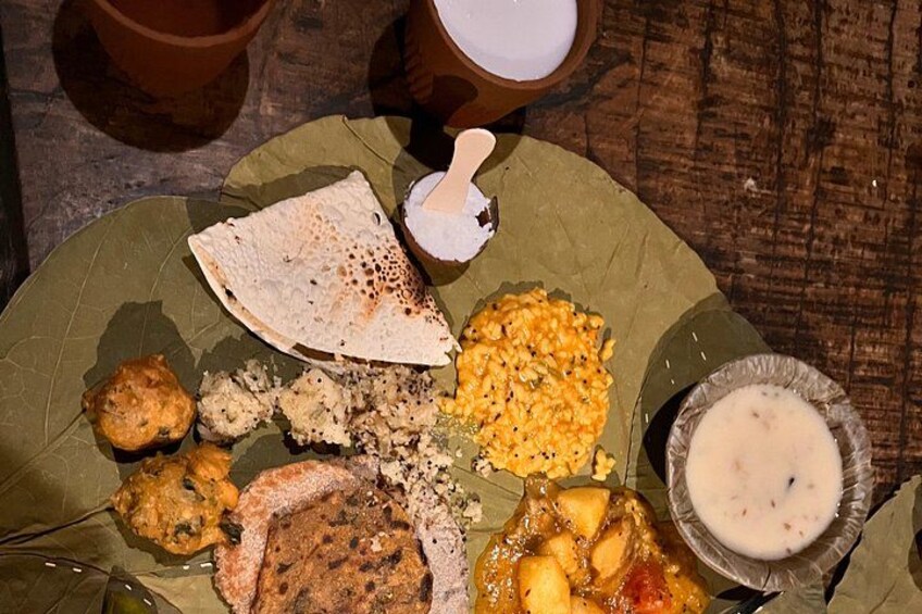 A traditional meal on a banana leaf with various dishes including flatbread, a curry, and a bowl of soup. 2