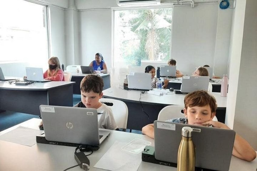 Ett klassrum där eleverna använder bärbara datorer vid sina skrivbord. 2