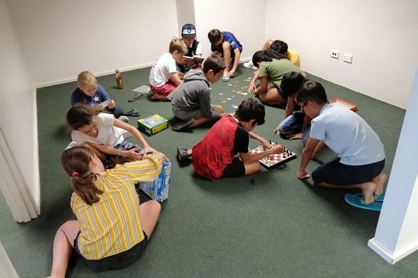 En grupp barn spelade ett brädspel i ett rum med grönt golv och vita väggar. 5