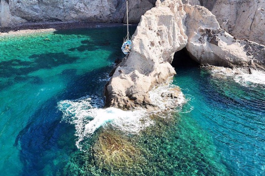 A boat tied to a rocky outcrop with clear turquoise water. 1