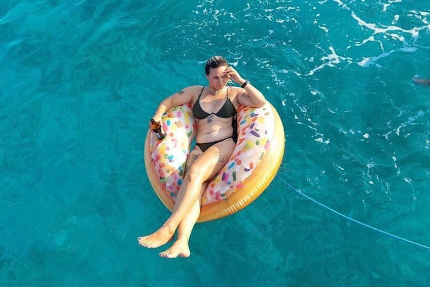 A person floating on a colorful inflatable ring in a clear blue pool. 5