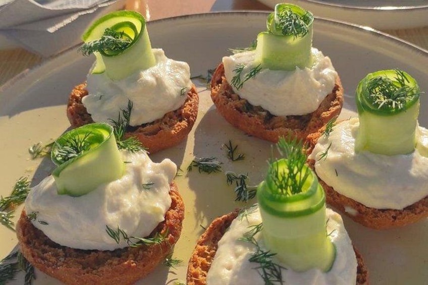 A plate of food with toast topped with cream and cucumber slices, garnished with dill. 3