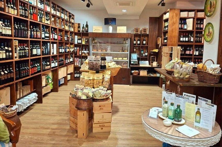 A store with wooden shelves stocked with various products, a display table with items, and a counter with brochures. 5