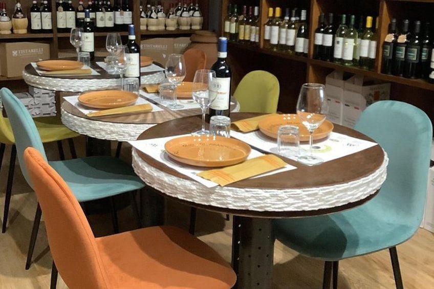 A restaurant interior with round tables, chairs, and wine bottles on shelves. 3