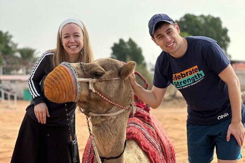 Two people with a camel in a sandy area. 5