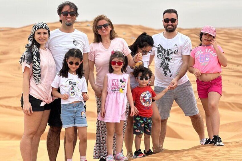 A family of seven in a desert setting with sand dunes in the background. 4