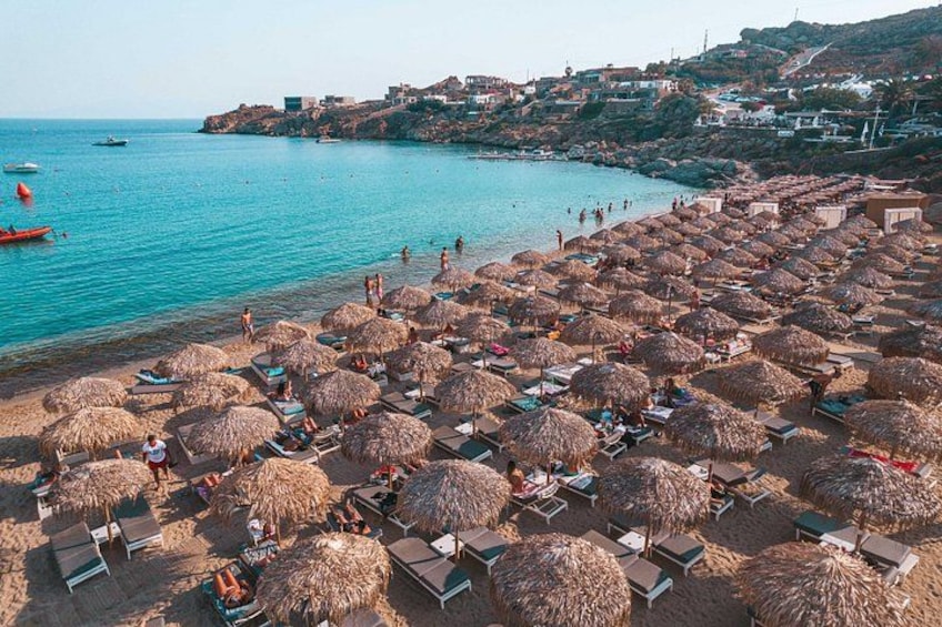 Una playa con sombrillas de paja y sillas de descanso. 5