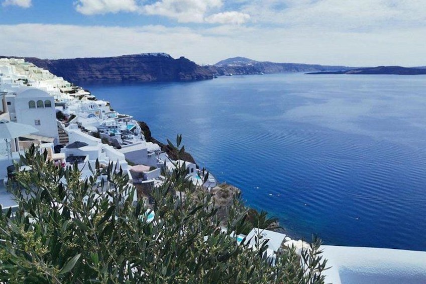A coastal village with white buildings, a clear blue sea, and distant mountains. 4