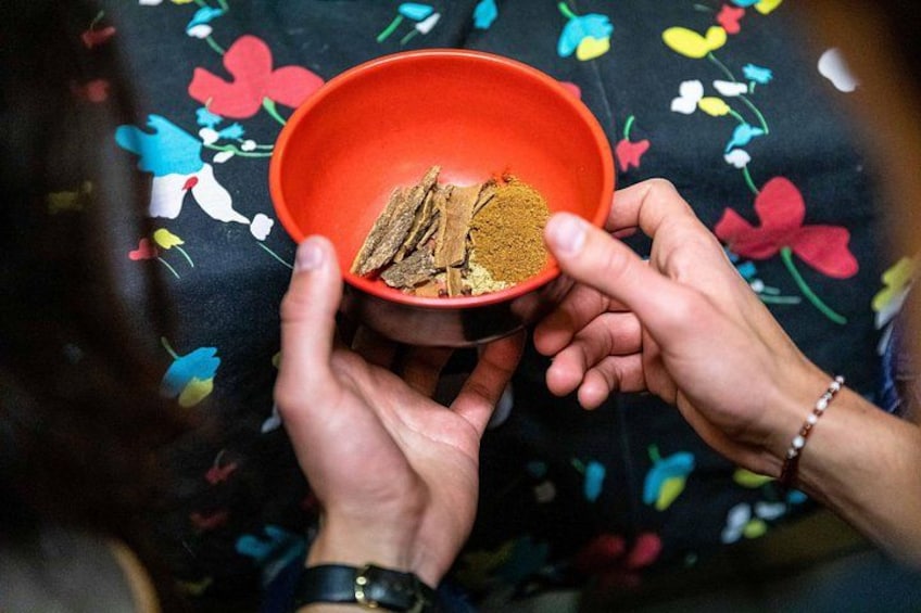 Two hands holding a red bowl with spices. 4