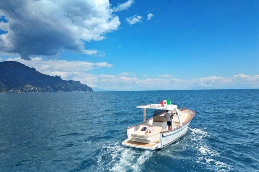 Un bote sobre aguas azules tranquilas con una costa montañosa al fondo. 3