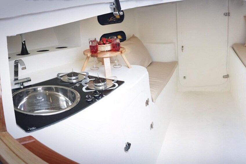 Cocina compacta con lavaplatos, estufa y una pequeña zona de comedor con mesa y sillas. 5