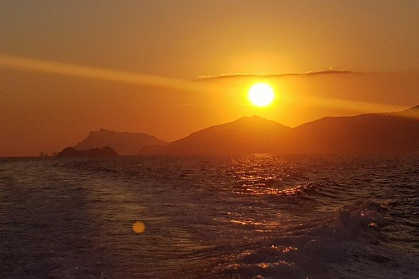 Una puesta de sol sobre el océano con montañas al fondo. 2