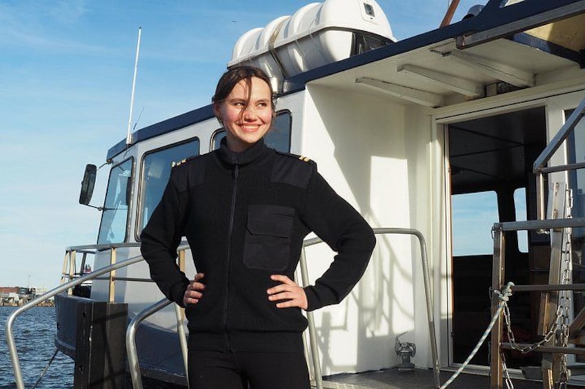 A person standing on a boat with a metal railing, a white cabin, and a clear sky. 3