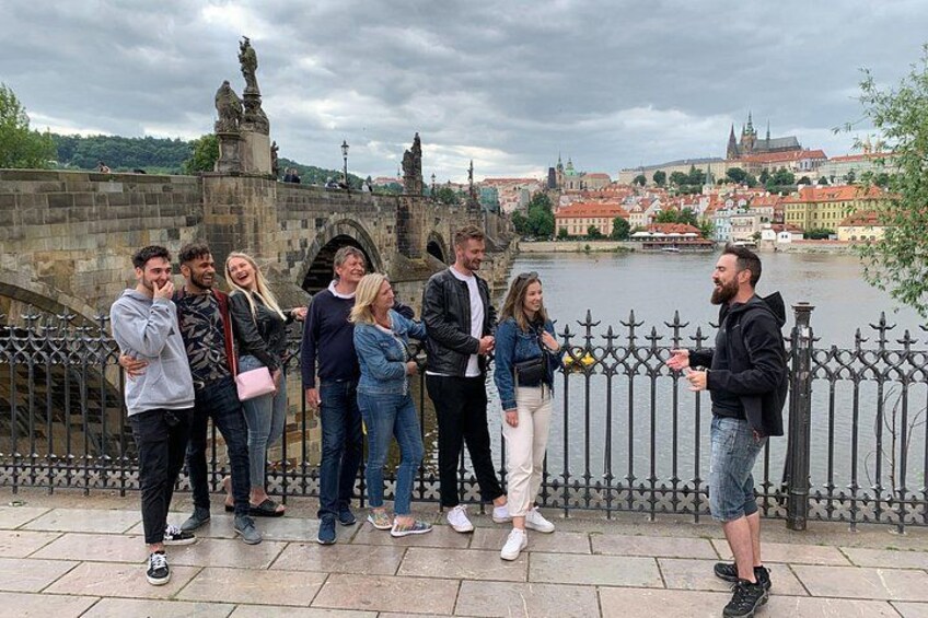 En grupp människor som står på en bro med en flod och en stadsbild i bakgrunden. 4