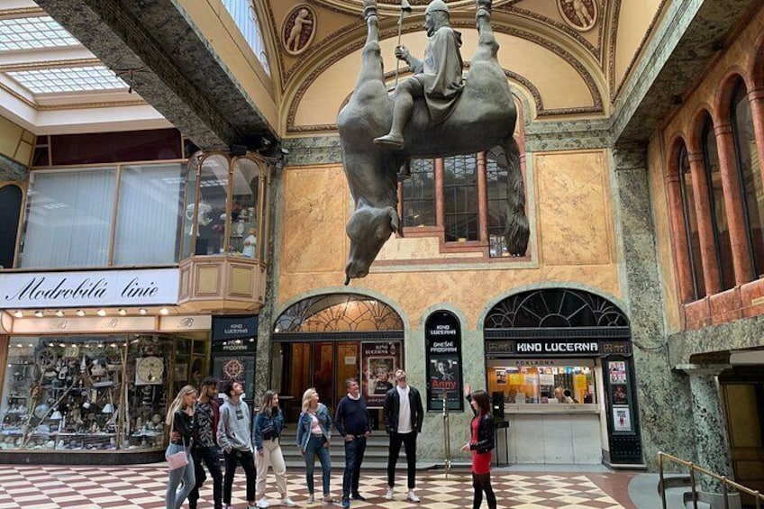 Ett område med butiker där det finns en stor staty av en man på hästryggen, en klocka och en butik som heter ”Monasteria Line”. 5