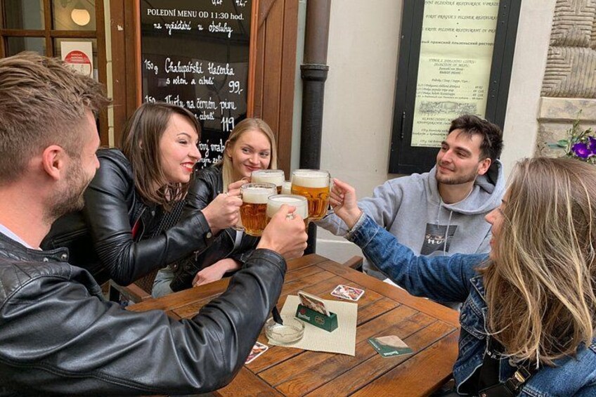 Un grupo de personas brindando con vasos de cerveza en una mesa de madera en un pub. 2