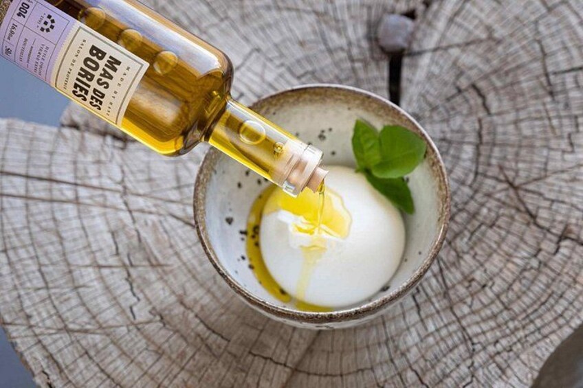 A bottle of Mas des Borries being poured into a glass with a white substance and a mint leaf. 1