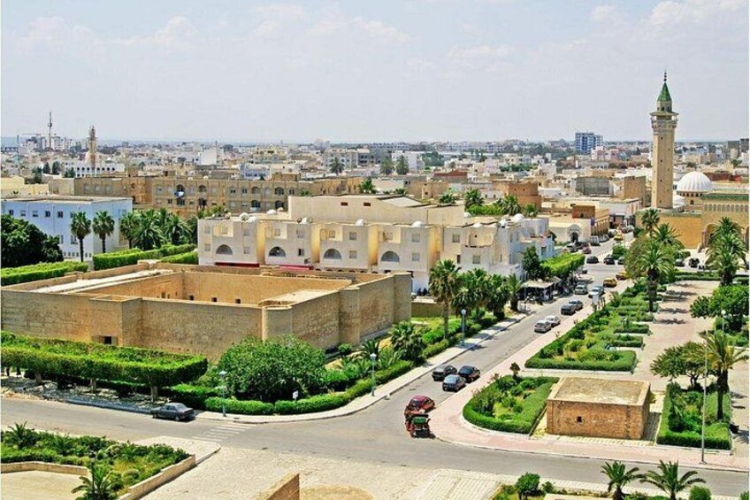 Une vue urbaine comprenant une mosquée imposante, une grande place ouverte et une rue animée où circulent des voitures. 3