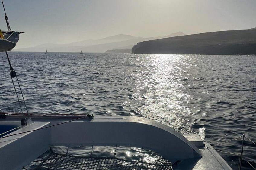 Un bateau sur une étendue d’eau calme, avec une côte montagneuse en arrière-plan. 3