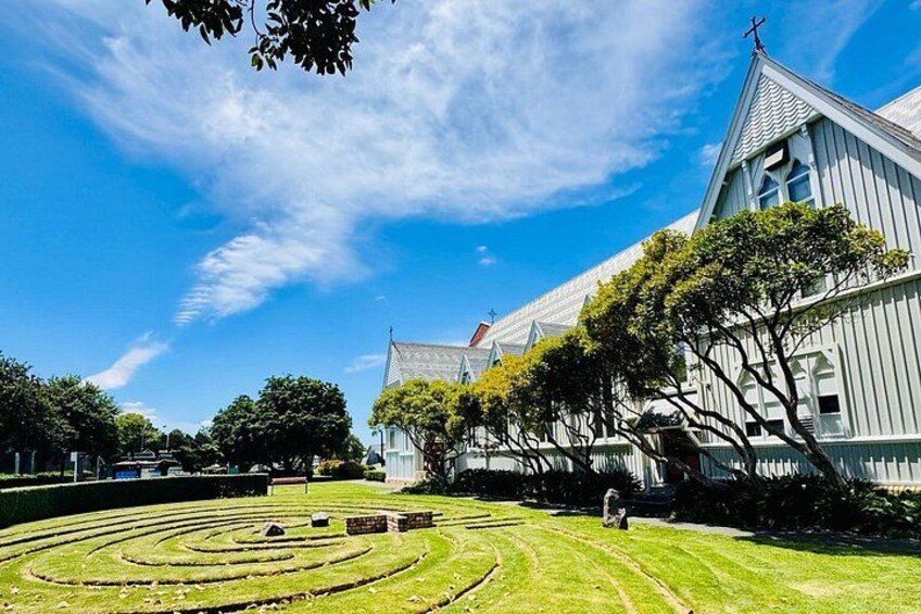A white building with a cross on top, surrounded by trees and a grassy area with a circular pattern. 4