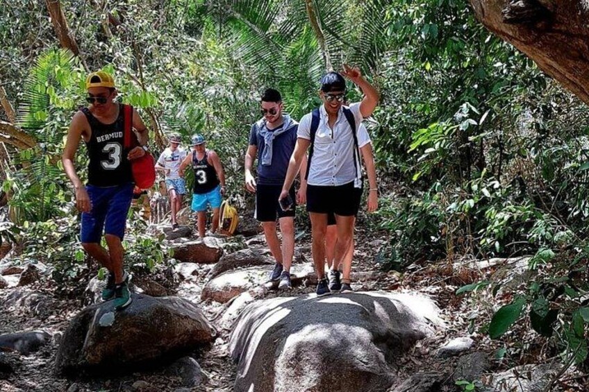 Des personnes font de la randonnée sur un sentier rocailleux, entouré d’une végétation dense. 4