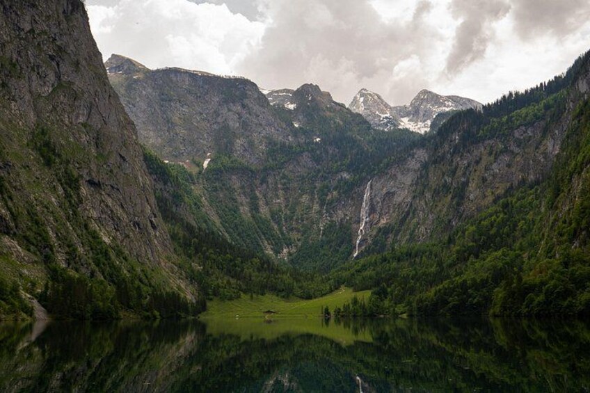 A mountainous landscape with a lake, a waterfall, and a forested valley. 2