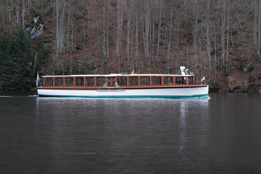 A wooden boat on a calm lake surrounded by trees. 4