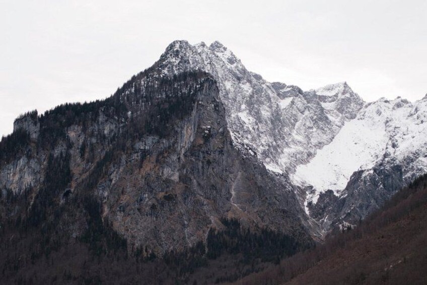 A rugged mountain range with snow-capped peaks and dense forested slopes. 3