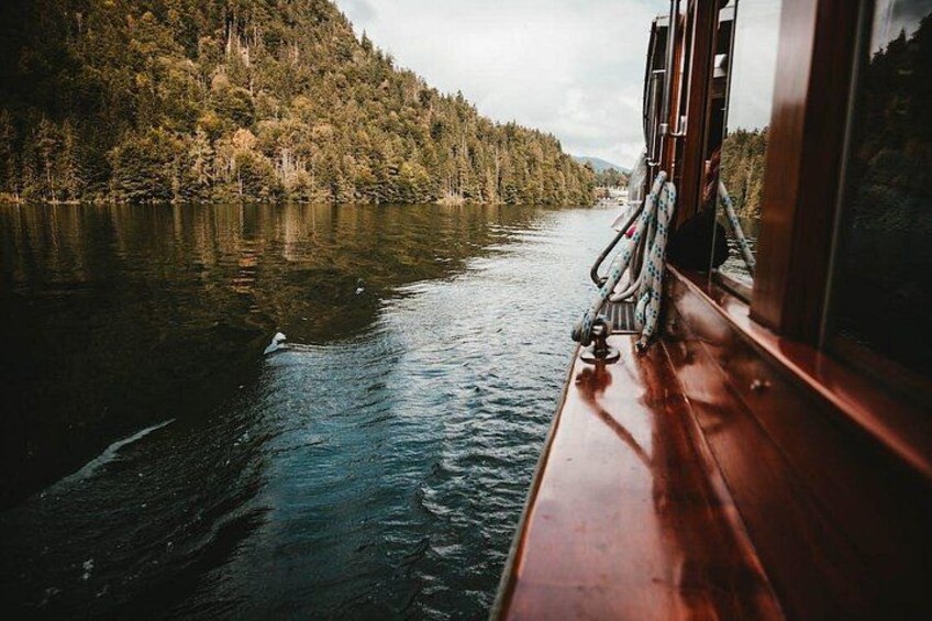 A calm river with a wooden boat docked on the right, surrounded by dense forest. 5