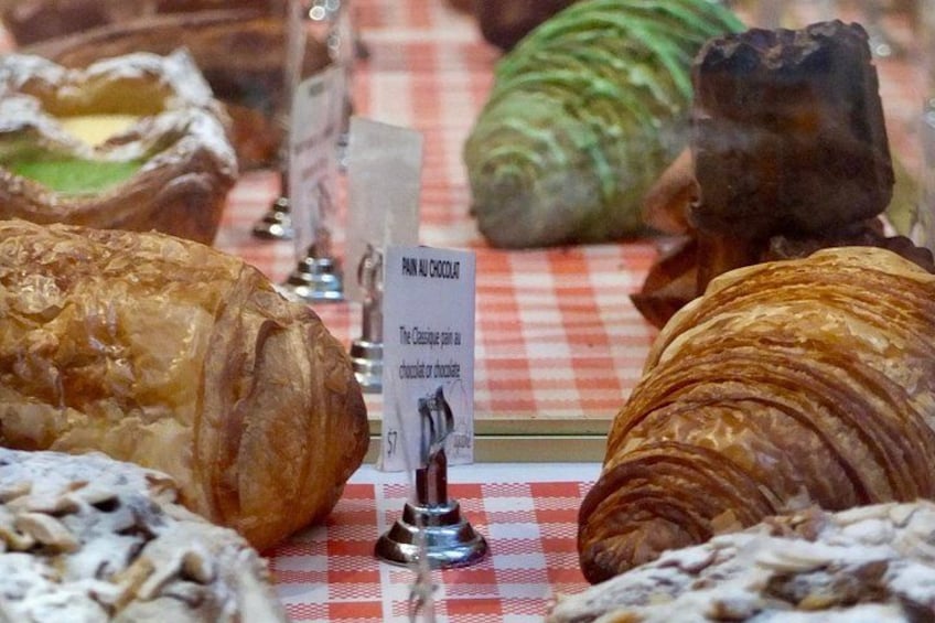 A variety of pastries displayed on a checkered tablecloth with a sign indicating a chocolate croissant. 2