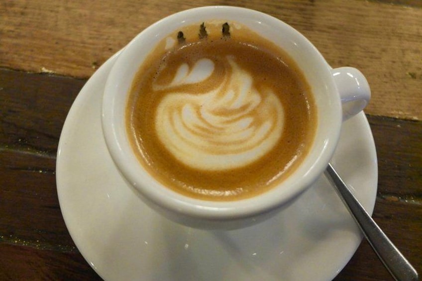 A cup of coffee with latte art on a saucer. 3