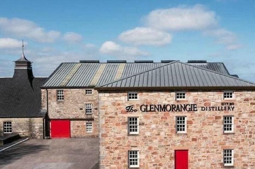 En bygning i sten med en røddør og teksten 'The Glenmorangie Distillery' på facaden. 4