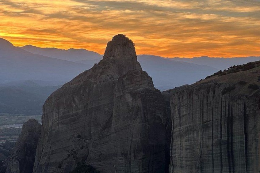A rock formation with a prominent peak, surrounded by other cliffs and mountains in the background. 4