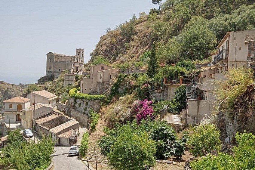 A hillside village with buildings, a road, and lush greenery. 1