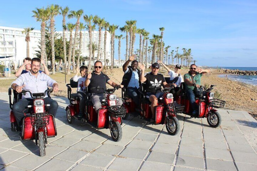 Un groupe de personnes se déplace sur des trottinettes électriques sur un chemin pavé, près de la plage. 1