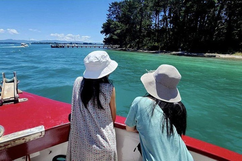 Two people on a boat, a red pier, and a forested shoreline. 3