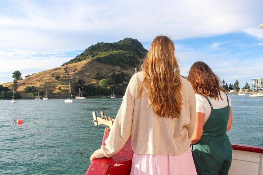 Two people on a boat, a body of water, and a hilly landscape with trees. 5