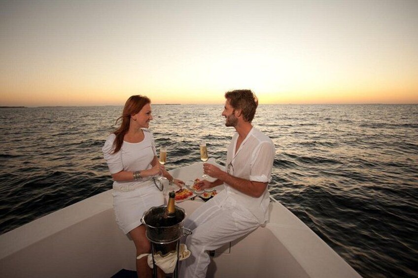 Two people on a boat at sunset, holding champagne glasses. 2