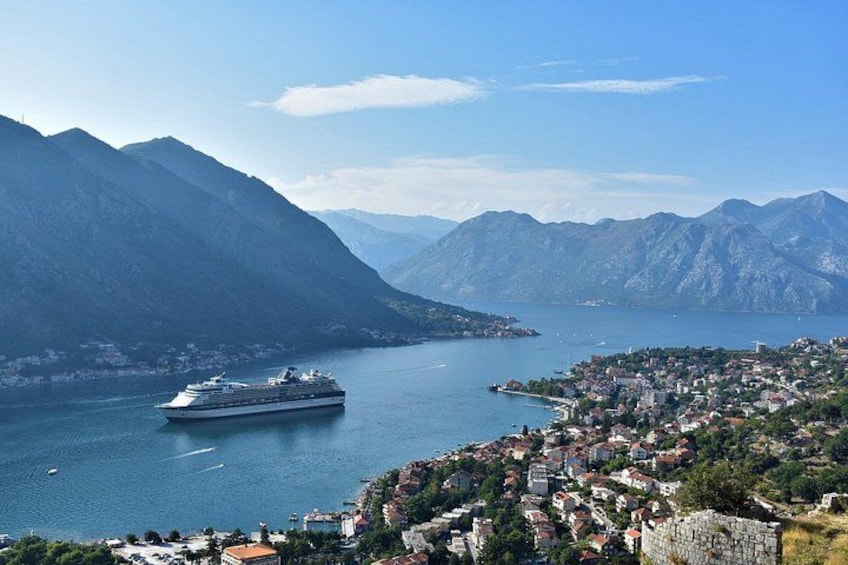 Un crucero navega en un lago tranquilo con montañas al fondo y un pueblo costero. 5