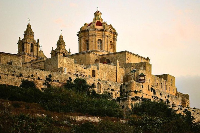 A historic church with a prominent dome and bell towers, surrounded by a fortified wall. 3