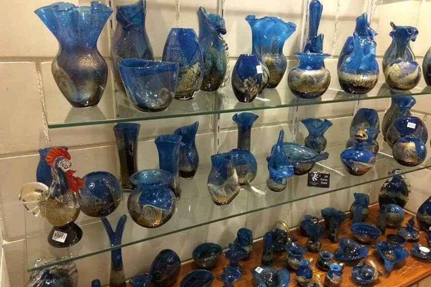 Verschillende blauwe glazen vazen en kommen staan op planken uitgestald. 3