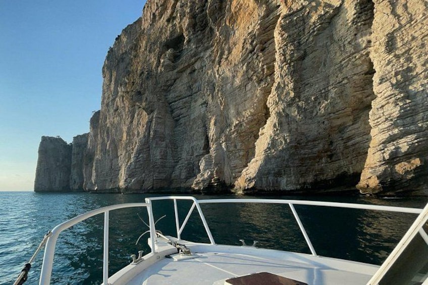 Un bateau sur une étendue d’eau calme, avec une falaise rocheuse en arrière-plan. 5