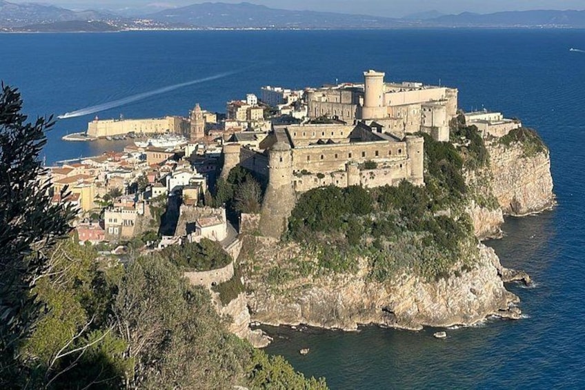 Une ville côtière qui abrite un château imposant, perché sur une falaise, et qui est entourée d’eau et de verdure. 1